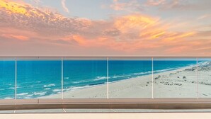 Ein Balkon mit Blick auf Strand und Meer bei Sonnenuntergang.