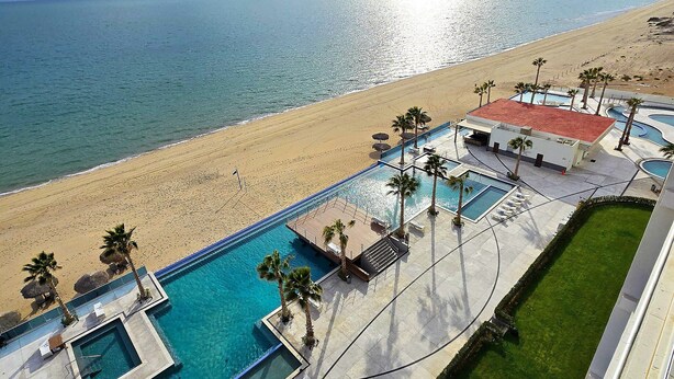Eine Luftaufnahme eines Resorts mit Poolbereich, Strand und blauem Himmel.