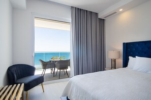 A hotel room with a bed, a chair, a table with drinks, a lamp, and a view of the sea. - Spectacular 2 Bedroom 2bathroom Beach Front Condominium at Encantame C1002 (Puerto Peñasco)