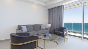 A modern living room with a grey sofa, two armchairs, a glass coffee table, and a view of the sea through large windows. - Spectacular 2 Bedroom 2bathroom Beach Front Condominium at Encantame C1002 (Puerto Peñasco)