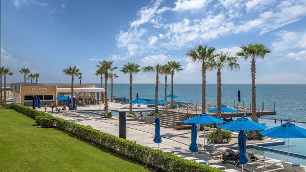 A resort with a pool area, palm trees, and a view of the ocean. - Encantame Towers Viento 1103 (Puerto Peñasco)