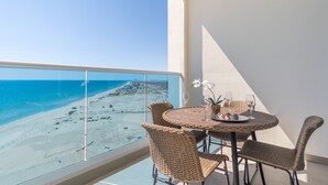 A balcony with a view of a beach and ocean. There is a round table with chairs and a small potted plant. - Encantame Towers Viento 1103 (Puerto Peñasco)