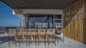 An outdoor seating area with wicker chairs and tables, overlooking the beach. - Encantame Towers Viento 1103 (Puerto Peñasco)