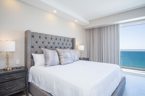 A modern hotel room with a large bed, two bedside tables with lamps, a grey upholstered headboard, and a view of the sea. - May The Force Be With You! The Galaxy Star Wars Theme at Encantame Towers C801 (Puerto Peñasco)
