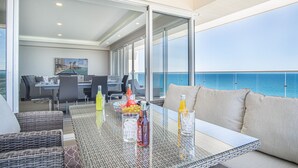 A balcony with a glass table, wicker chairs, and a sofa. There is a dining area in the background with a painting and a view of the sea. - May The Force Be With You! The Galaxy Star Wars Theme at Encantame Towers C801 (Puerto Peñasco)