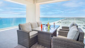 A balcony with wicker furniture, a glass table, and a view of the beach and ocean. - May The Force Be With You! The Galaxy Star Wars Theme at Encantame Towers C801 (Puerto Peñasco)