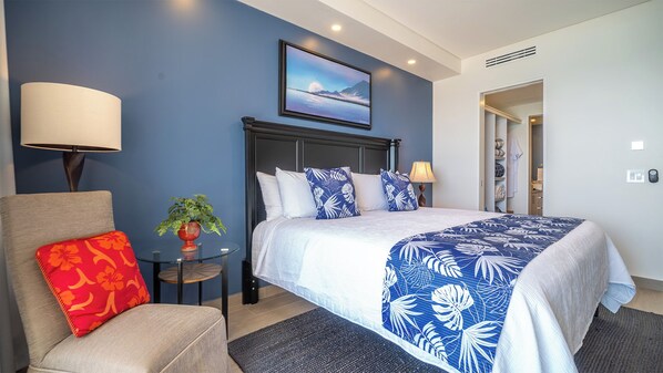 Une chambre d’hôtel avec un lit, une chaise, une petite table avec une plante et un tableau au mur.