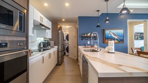 Eine moderne Küche mit Edelstahlgeräten, einer Marmorarbeitsplatte und einer blauen Akzentwand.