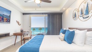 A hotel room with a bed, a desk, and a chair. There is a balcony with a view of the ocean. - Unique Condo by the Beach at Encantame Towers C305 (Puerto Peñasco)
