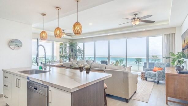 A modern kitchen with a large island, a dining area with a view of the ocean, and a living room with a sofa and a coffee table. - Unique Condo by the Beach at Encantame Towers C305 (Puerto Peñasco)