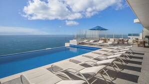 Ein Poolbereich mit Liegestühlen und Blick auf den Ozean.