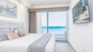 Une chambre avec un grand lit, une vue sur la plage et un tableau accroché au mur.