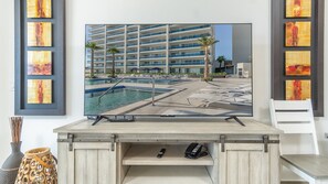 A flat-screen TV mounted on a wooden cabinet with a poolside view, a telephone, and a lamp. - A Sanctuary Of Tranquillity Encantame Viento 404 (Puerto Peñasco)