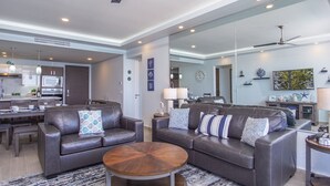 Een moderne woonkamer met leren banken, een salontafel en een eethoek, met een keuken op de achtergrond.