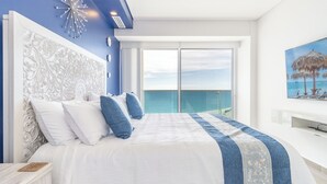 A bedroom with a large bed, a view of the sea through a balcony, and a painting of a beach scene. - Encantame Towers Viento 801 (Puerto Peñasco)