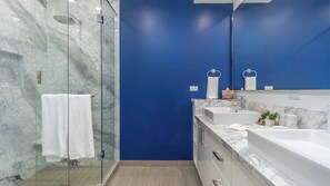 Ein modernes Badezimmer mit Duschkabine aus Glas, Marmorplatten und einer blauen Akzentwand.