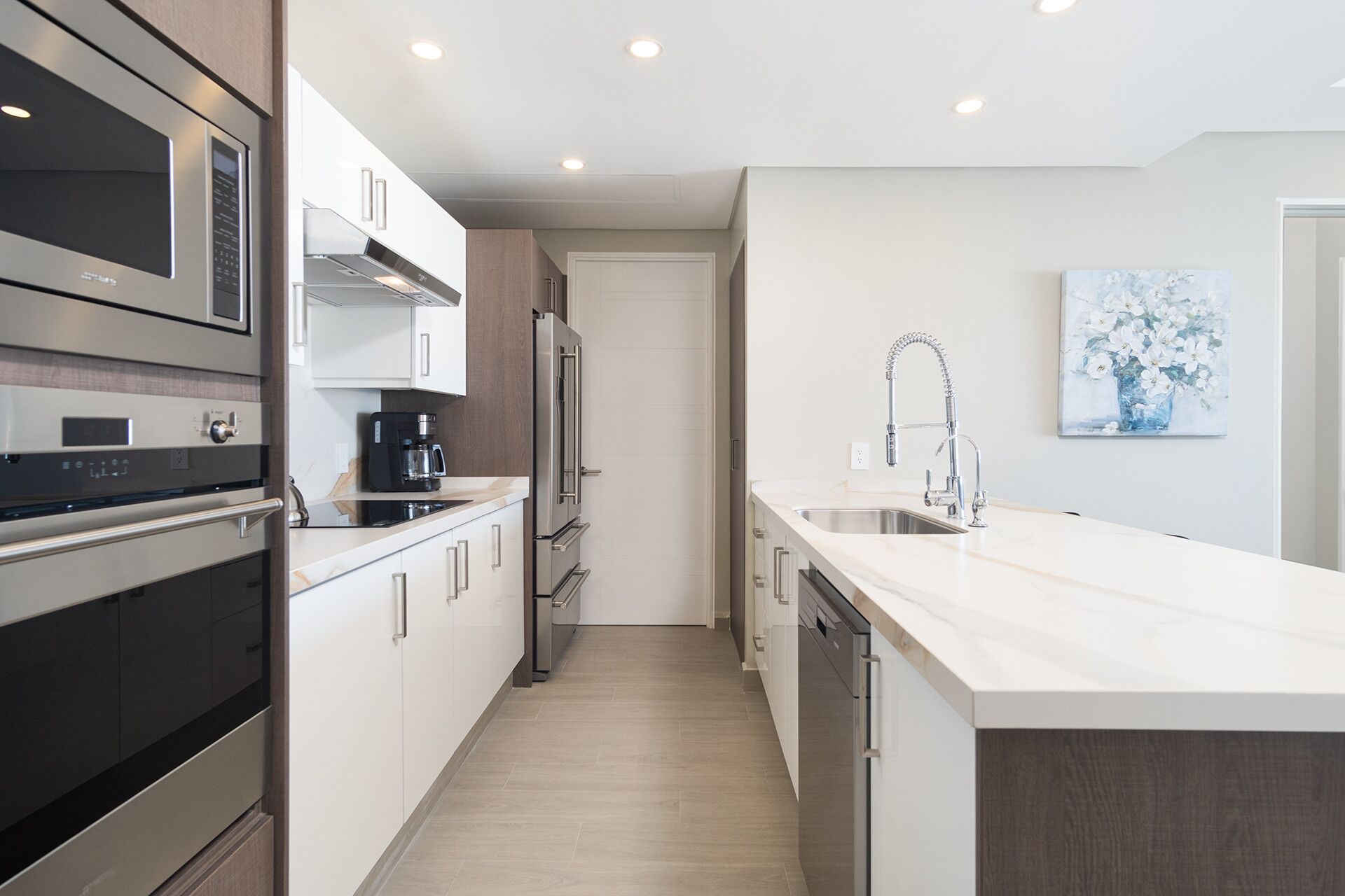 Una cocina moderna con electrodomésticos de acero inoxidable, lavavajillas y una isla grande con fregadero.