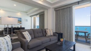 A modern living room with a grey sofa, a coffee table, and a laptop. There is a balcony with a view of the sea. - Splash in The New Lazy River and Sleep In Luxury Encantame Towers C 1203 (Puerto Peñasco)