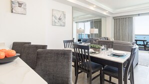A modern dining area with a table set for four, a sofa, and a view of the sea. - Splash in The New Lazy River and Sleep In Luxury Encantame Towers C 1203 (Puerto Peñasco)