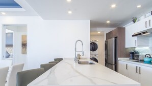 A modern kitchen with a marble countertop, stainless steel appliances, and a built-in washing machine. - Looking for the Perfect Scape From the City? Peaceful 2 Bedroom Condo Verano 804 (Puerto Peñasco)