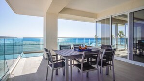 A balcony with a table and chairs, overlooking a beach and the ocean. - Awesome 3 Bedroom Condo Encantame Tower E 201 (Puerto Peñasco)