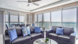 A modern living room with leather sofas, a glass coffee table, and large windows offering a view of the sea. - Awesome 3 Bedroom Condo Encantame Tower E 201 (Puerto Peñasco)