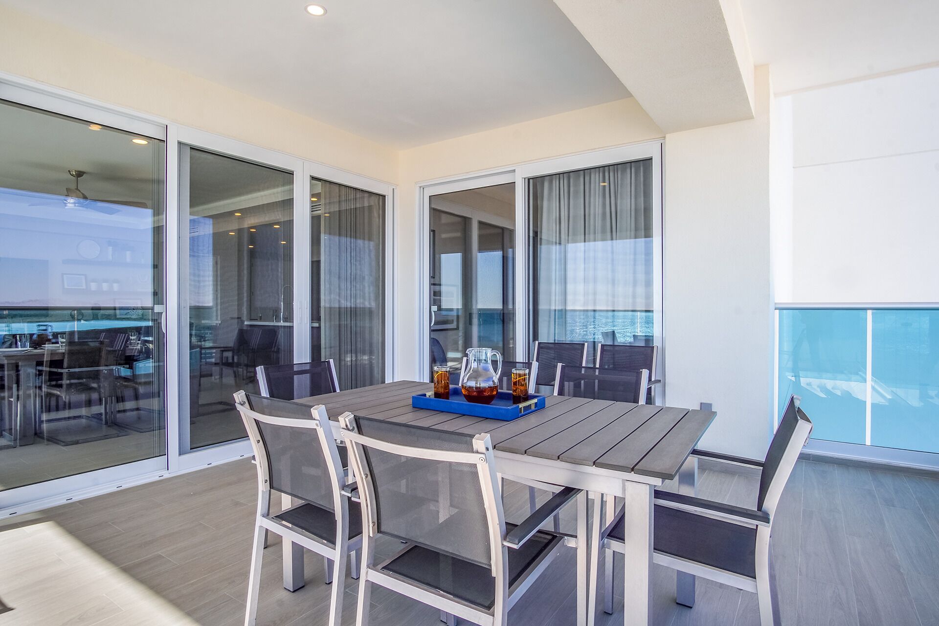 A balcony with a table set for two, featuring a pitcher and glasses.