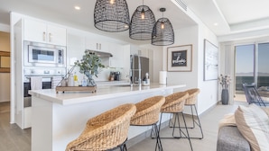 A modern kitchen with a central island, bar stools, and hanging pendant lights. - Wonderful 1 Bedroom Condominium Encantame Verano 2103 (Puerto Peñasco)