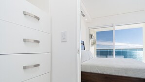 Une chambre à coucher moderne avec une grande fenêtre, un lit et une armoire blanche.