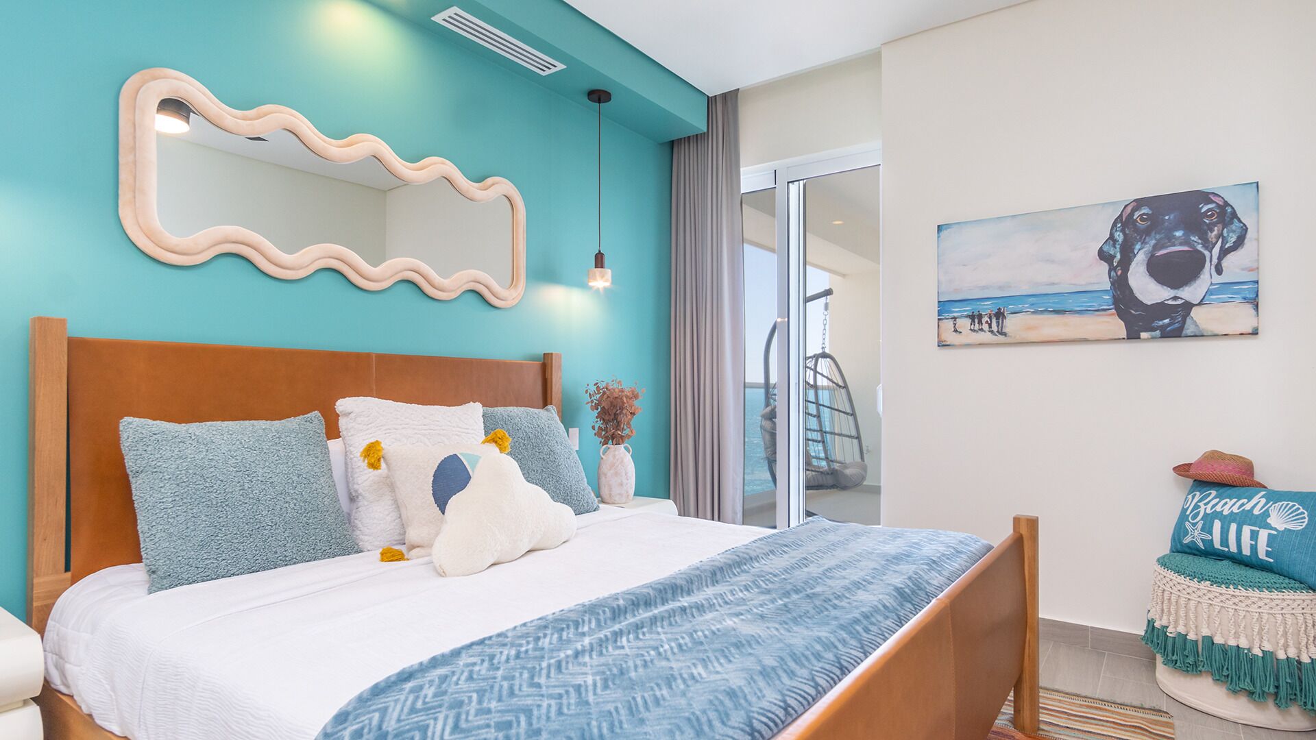 A bedroom with a wooden headboard, a large mirror, and a beach-themed painting.