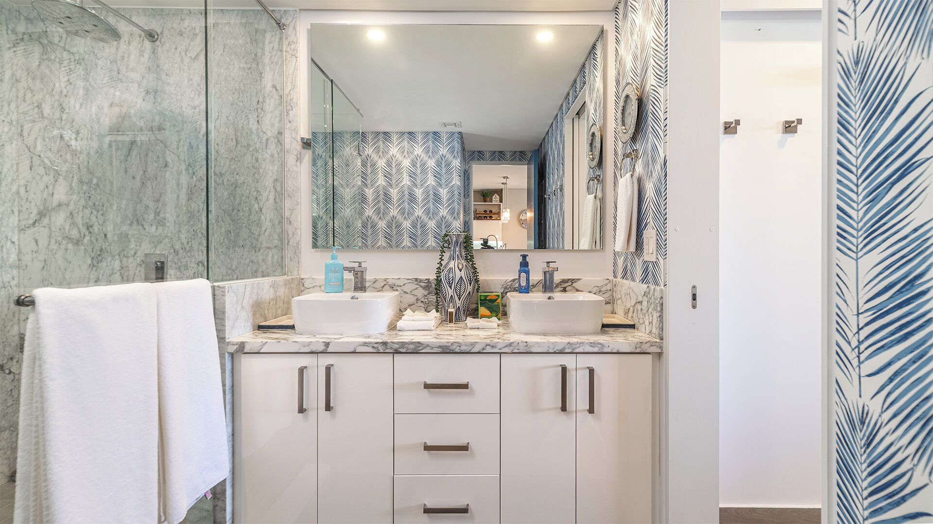 Un baño moderno con dos lavamanos, un espejo grande y una zona de ducha.