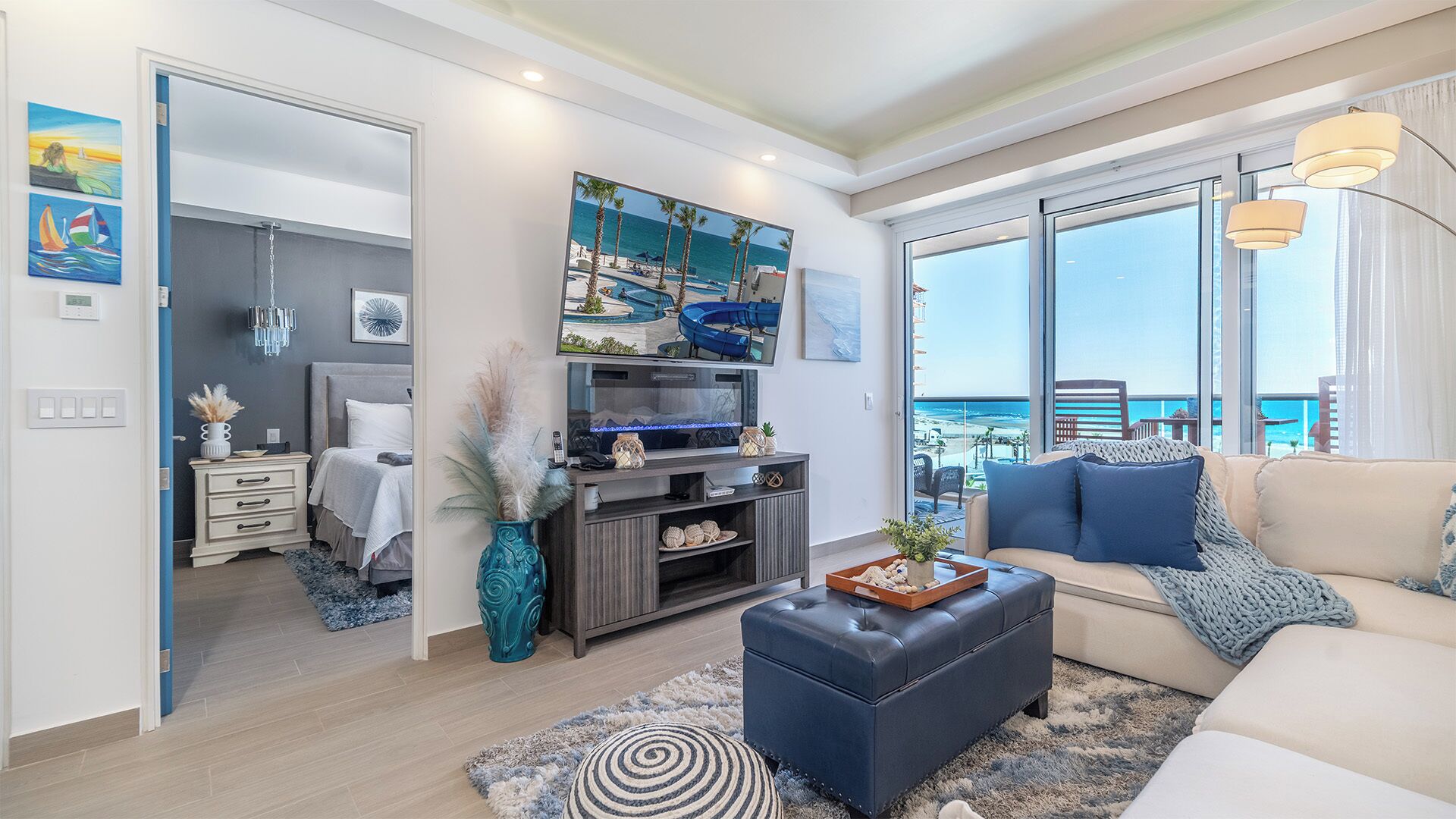 A modern living room with a large TV, a sofa, and a view of the sea.