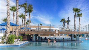 A pool area with palm trees, umbrellas, and lounge chairs. - Phenomenal 3 Bedroom Condo Encantame Tower E 101 (Puerto Peñasco)
