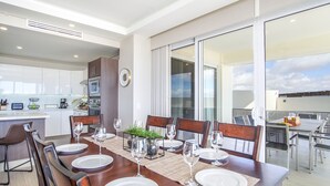 A modern dining area with a large table set for six, surrounded by wooden chairs. - Phenomenal 3 Bedroom Condo Encantame Tower E 101 (Puerto Peñasco)