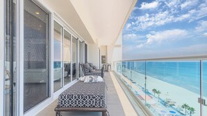 A balcony with a view of the ocean, a sofa, and a chair.