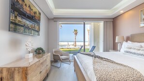 A hotel room with a large bed, a desk, a chair, and a view of the beach. - Encantame Towers Viento 105 (Puerto Peñasco)
