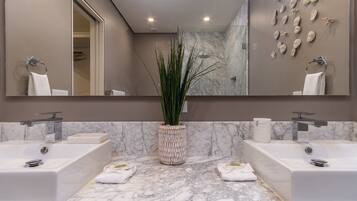 A bathroom with two sinks, a large mirror, and a decorative plant in the center.