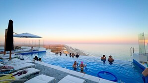 An infinity pool with a view of the beach at sunset. - Stunning 2 Bedroom Corner Beach Front Condominium Encantame C-1105 (Puerto Peñasco)