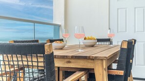 Een houten tafel met twee schalen met snacks en twee glaasjes roze drank, omringd door rieten stoelen.