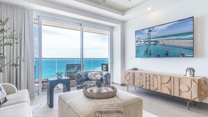 Ein geräumiges Wohnzimmer mit großem Fenster und Meerblick, ein bequemes Sofa, ein Couchtisch und ein modernes Sideboard.