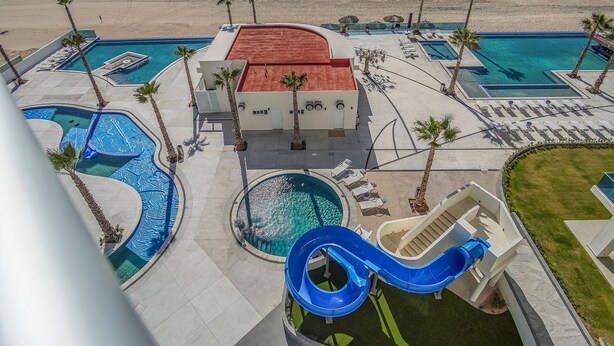 A resort with multiple swimming pools, a water slide, and a beach view. - Sublime 3 Bedroom Condo Encantame Towers Verano 801 (Puerto Peñasco)