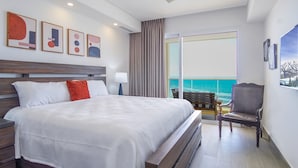 Une chambre d’hôtel avec un grand lit, une chaise, un bureau et une vue sur l’océan.