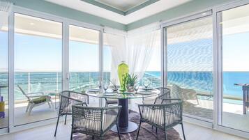 Un comedor con mesa de vidrio, sillas y vista al mar.