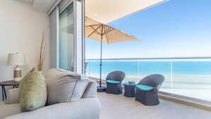 A balcony with a sofa, two wicker chairs, a table, and an umbrella. - Beach Getaway 2 Bedroom Condo W802 (Puerto Peñasco)