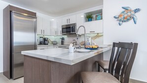A modern kitchen with a central island, stainless steel appliances, and a decorative turtle wall art piece.
