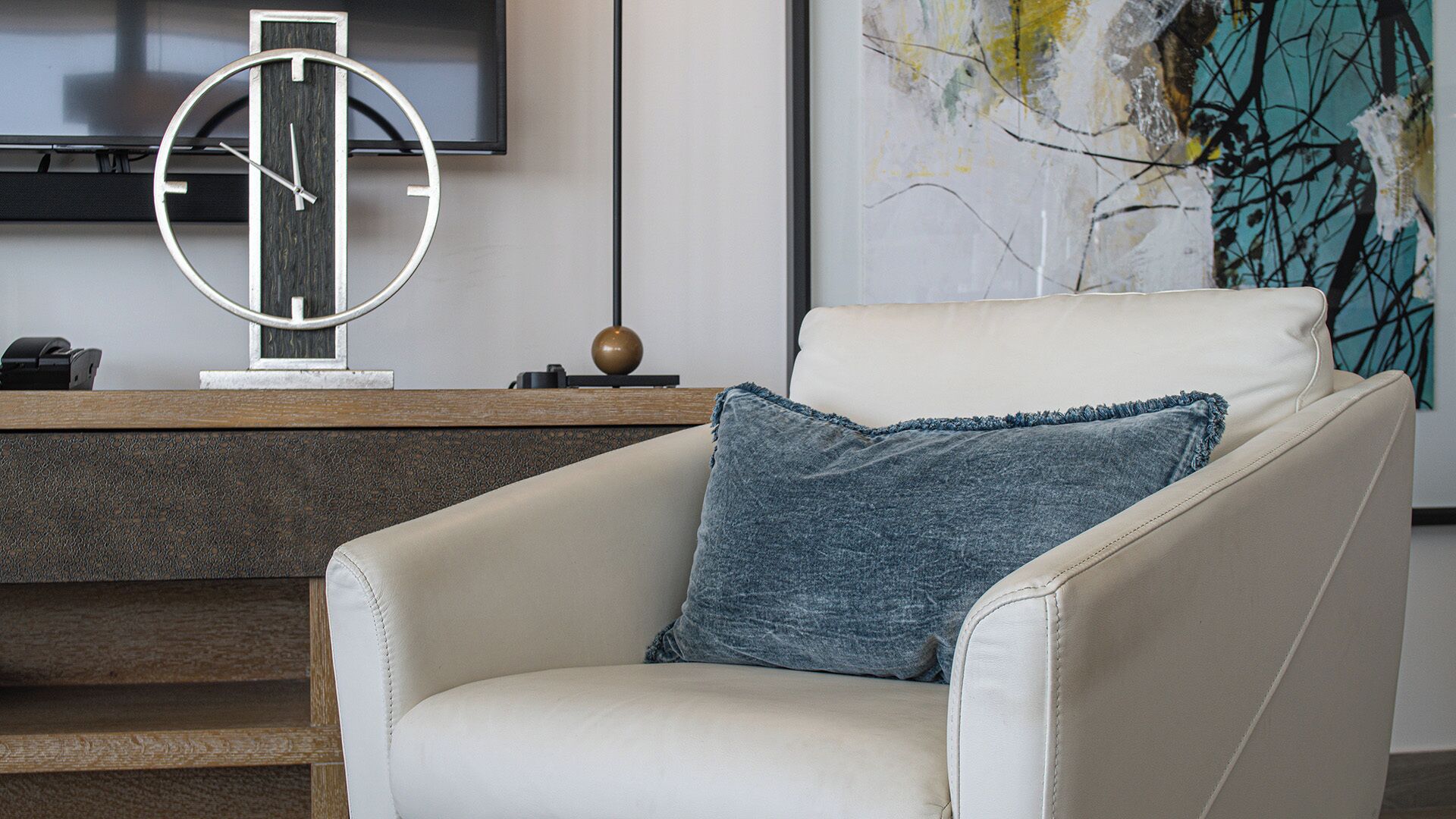 Un salon moderne avec un fauteuil en cuir blanc, une horloge murale ronde et une décoration minimaliste.