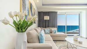 A modern living room with a beige sofa, a round coffee table, and a large window offering a view of the sea. - A Style Of Its Own 2 Bedroom Unit Encantame Viento 1202 (Puerto Peñasco)