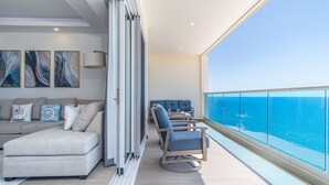 A balcony with a view of the ocean, a sofa, and a table with chairs. - A Style Of Its Own 2 Bedroom Unit Encantame Viento 1202 (Puerto Peñasco)