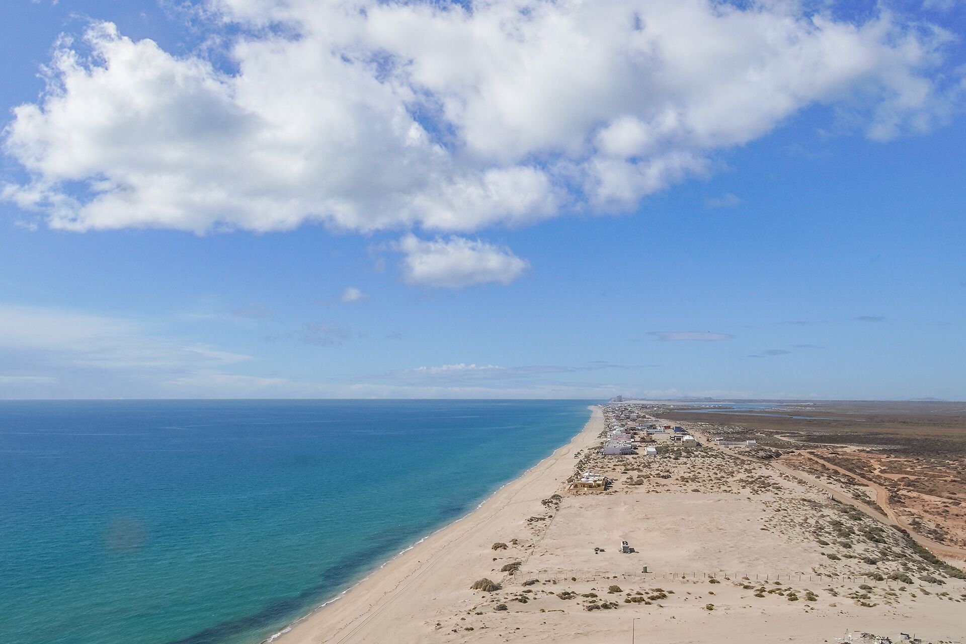 Un paysage côtier avec une plage de sable et un ciel bleu dégagé.