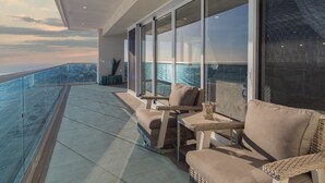 A balcony with wicker furniture, large windows, and a view of the water. - Impressive & Beautiful 3 Bedroom end Unit Ocean Front Encantame C-1901 (Puerto Peñasco)